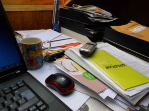 Ein Schreibtisch voller Unterlagenstapel ohne Arbeitsorganisation